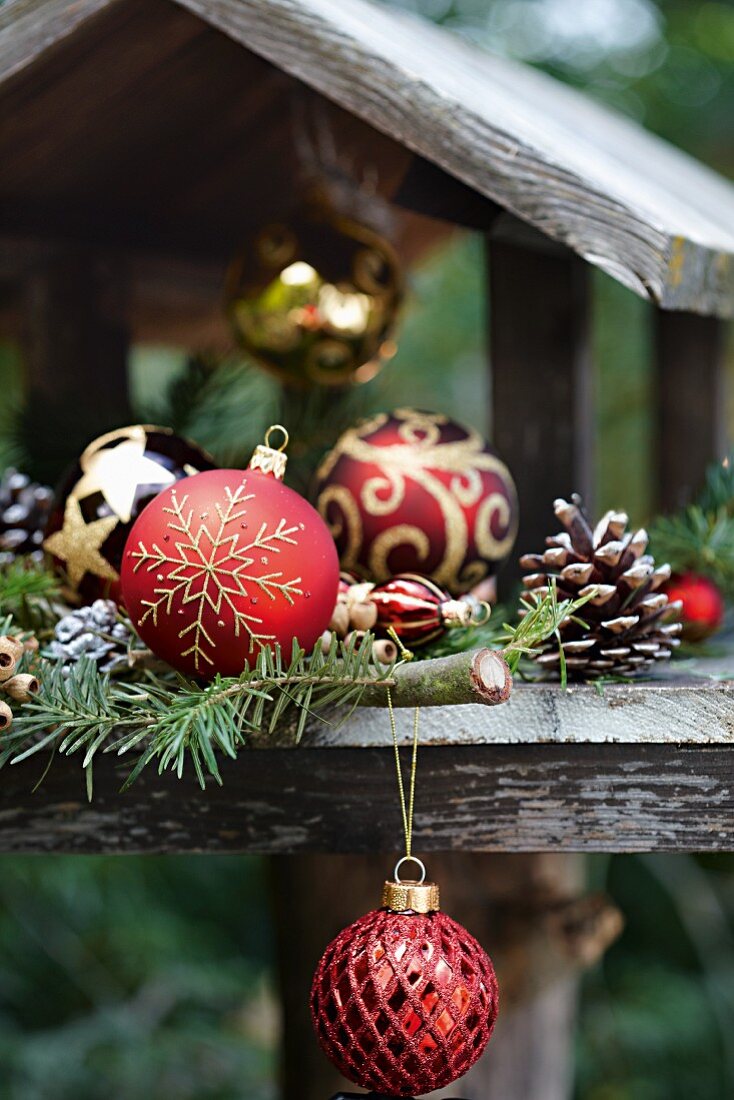 Weihnachtlich geschmücktes Vogelhäuschen mit Christbaumkugeln