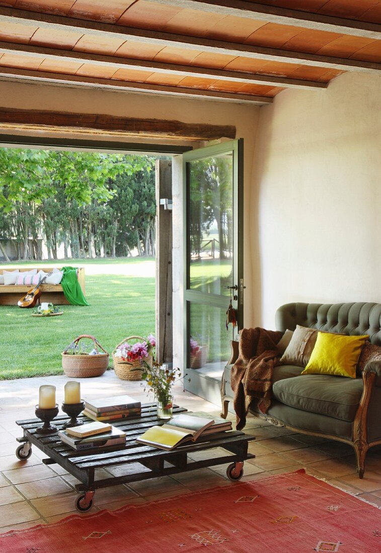 Sofa und Palettentisch vor geöffneten Terrassentüren