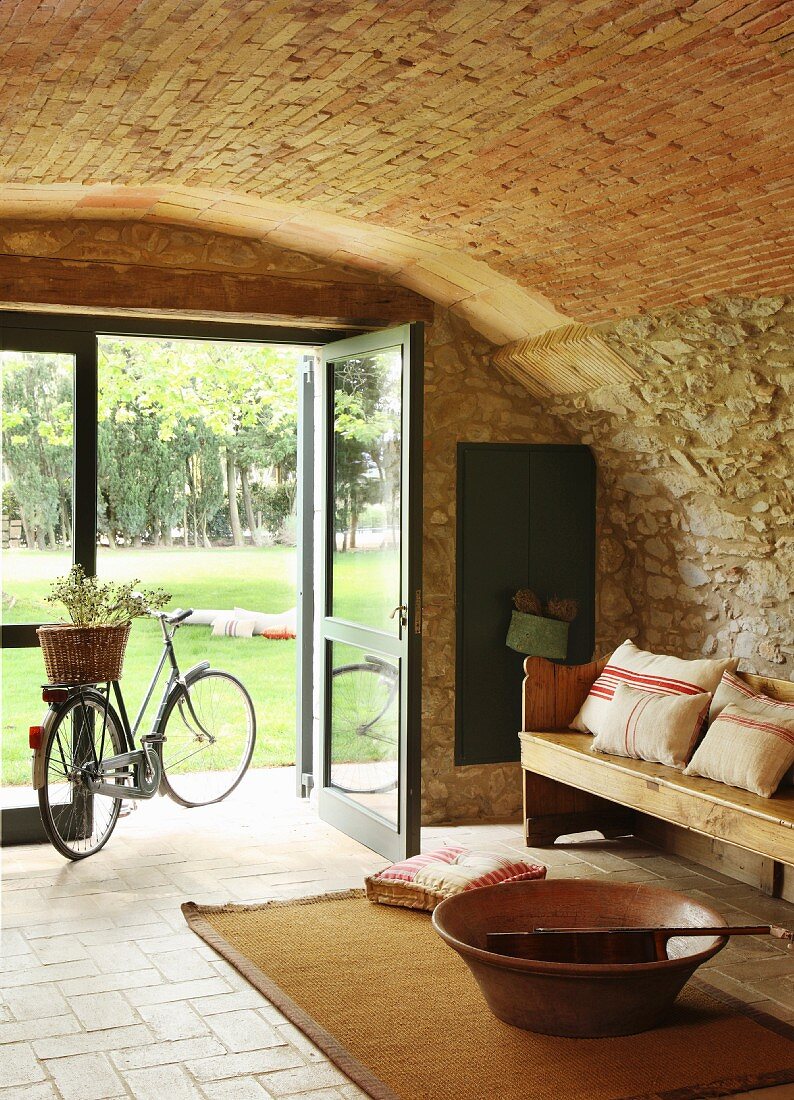 Bicycle and wooden bench in front of open glass door in vaulted foyer