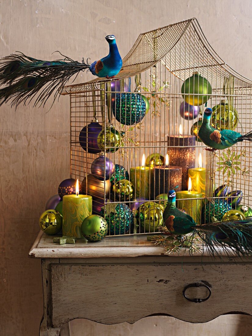Baubles, candles and peacock figurines decorating bird cage