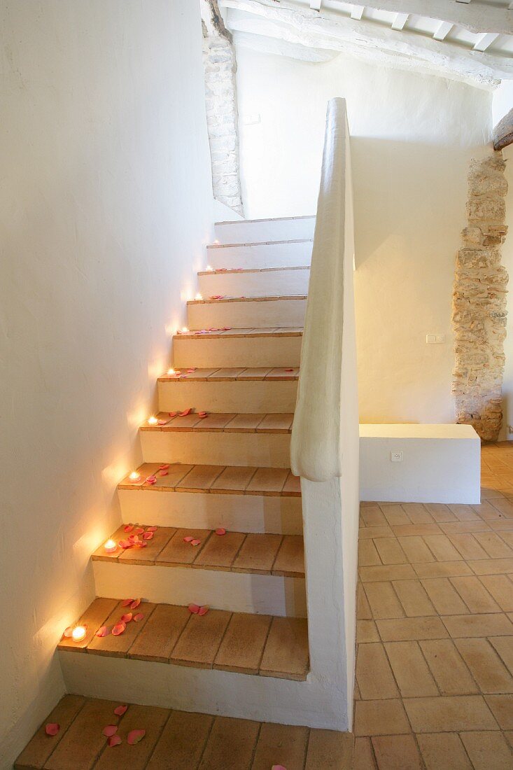Staircase romantically decorated with tealights and rose petals in old, restored building
