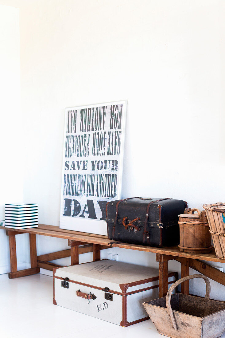 Suitcases, baskets and framed motto on wooden bench