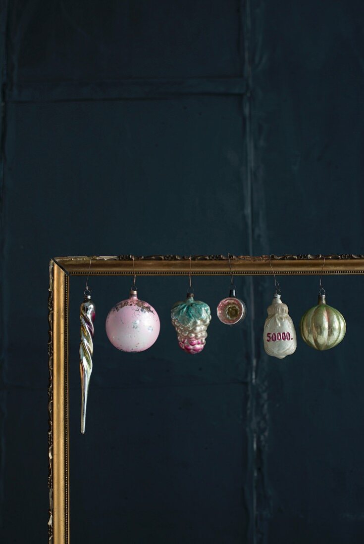 Old Christmas decorations hung in gilt picture frame