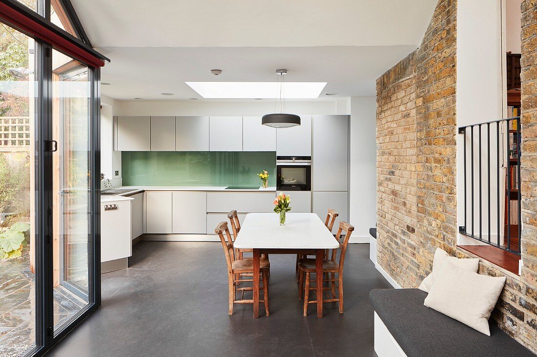 Esstisch in minimalistischer Küche mit Backsteinwand