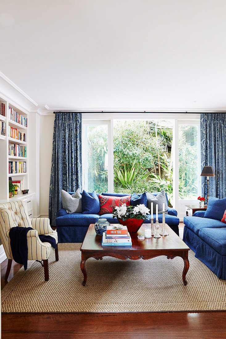 Blue upholstered furniture, antique coffee table and armchair in the living room