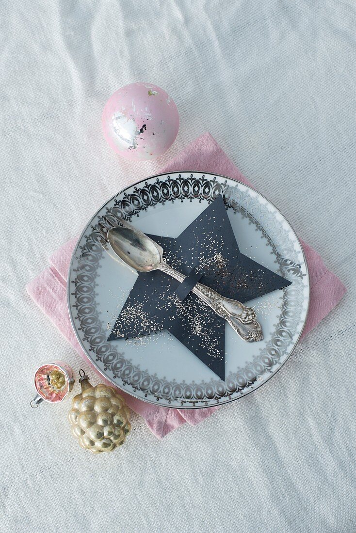 Paper star-shaped cutlery holder on plate with vintage decorations