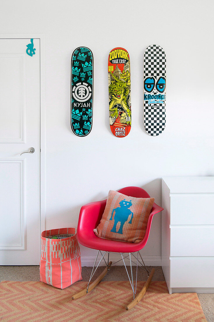 Drei Skateboards über rotem Designer-Schaukelstuhl