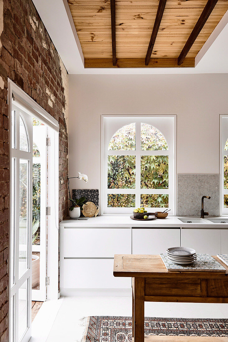 Arched window in the kitchen with brick wall and wooden table