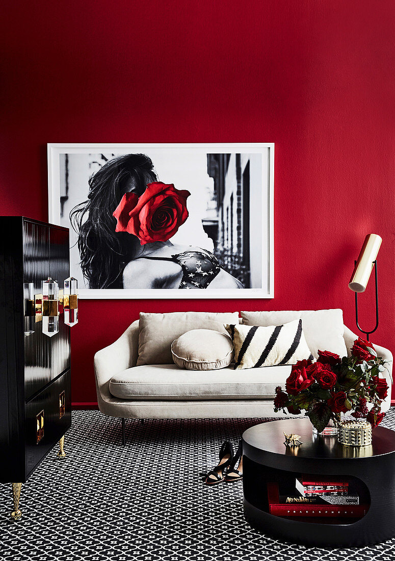 Black coffee table, black cupboard and bright sofa in the living room with red wall