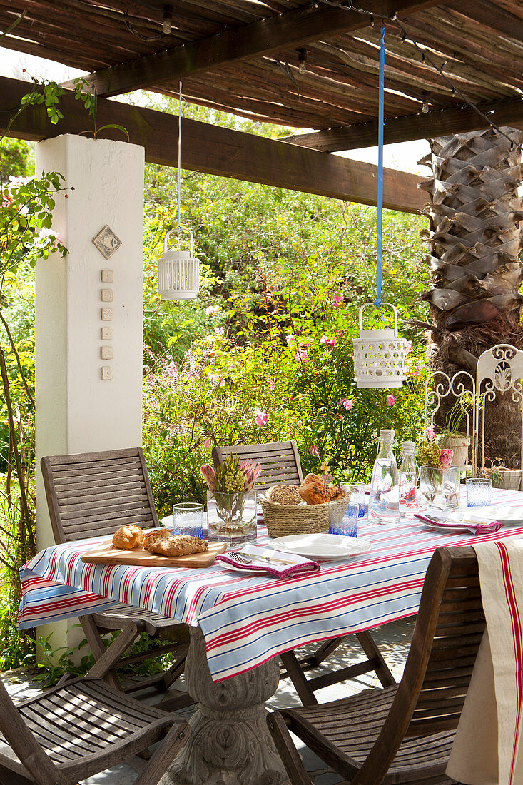 Gedeckter Tisch auf überdachter Terrasse im Sommergarten