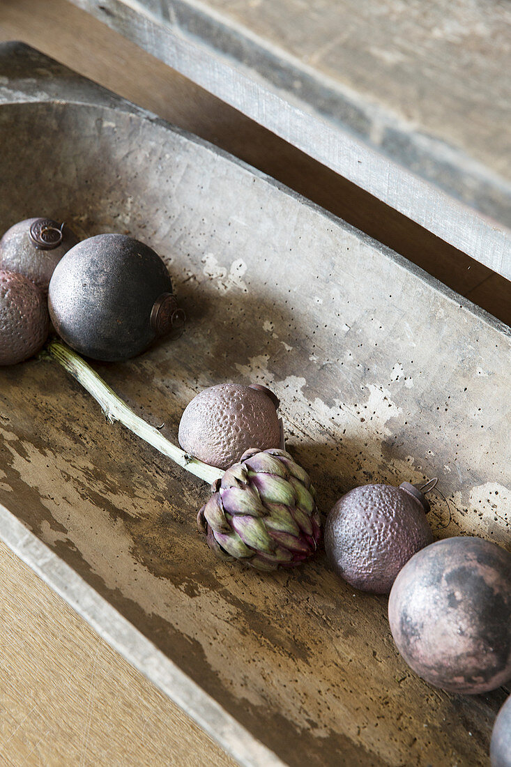 Purple Christmas-tree baubles and artichoke in wooden trough