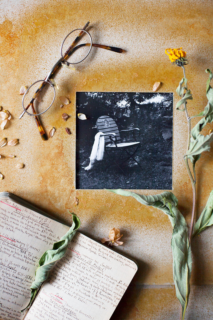 Black-and-white photo in hand-made frame, dried flowers, note book and spectacles