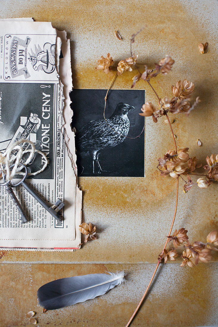 Black-and-white photo in hand-made frame, dried flowers, newspaper and keys