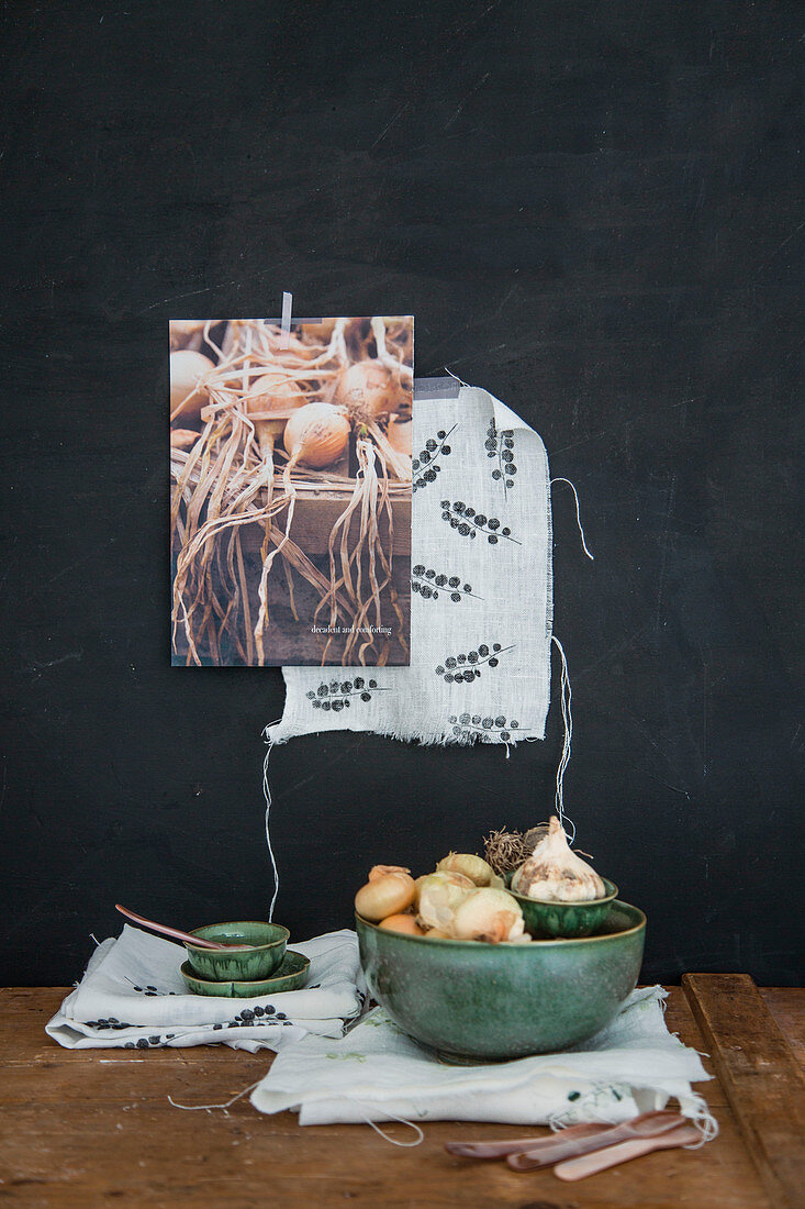 Green bowl of onions and garlic on printed cloth