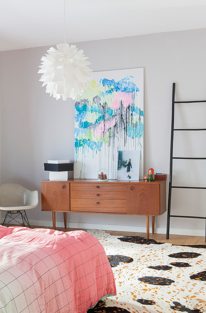 Abstract painting on top of retro sideboard in bedroom
