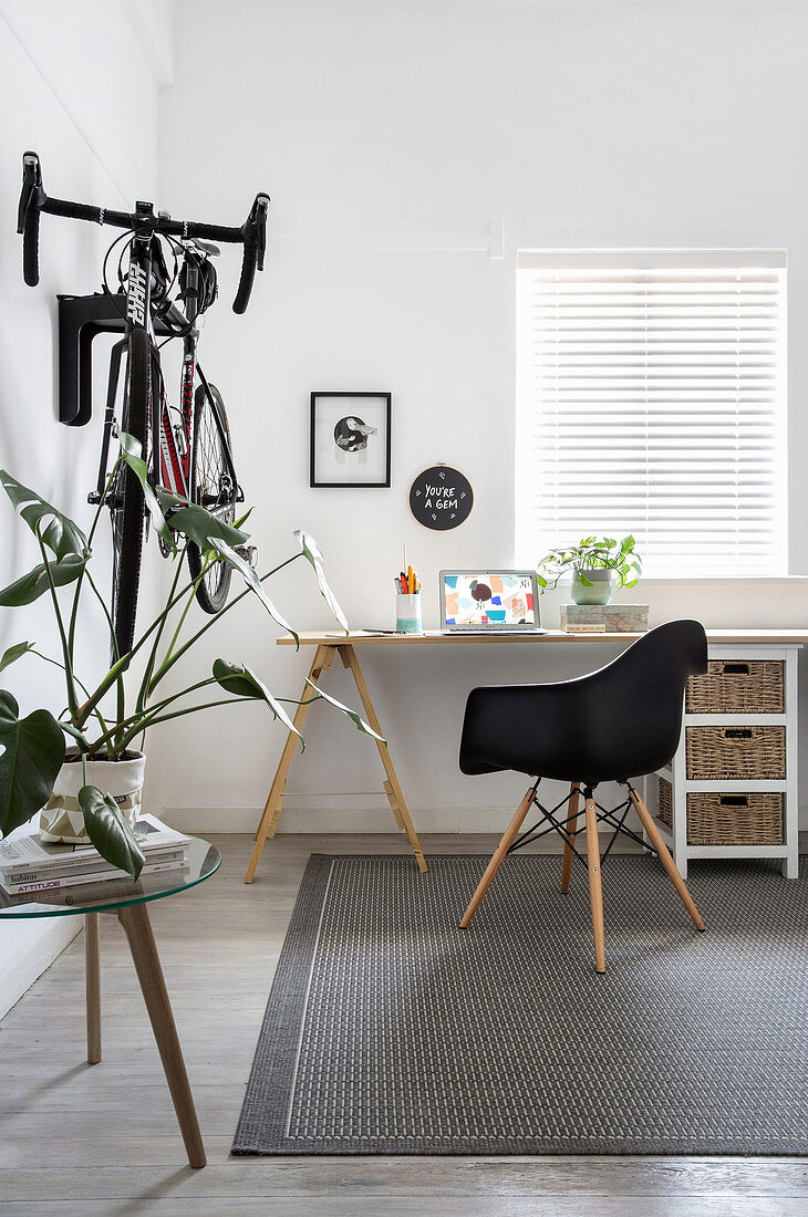 Arbeitszimmer mit schlichtem Schreibtisch und Klassikerstuhl, Fahrrad an der Wand