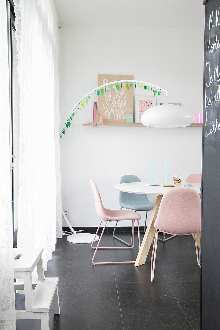 Arc lamp over dining table with upholstered chairs in pastel shades