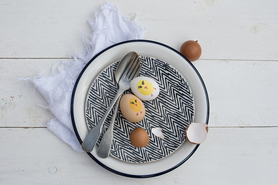 Cutlery, painted Easter eggs and egg shells on vintage plate
