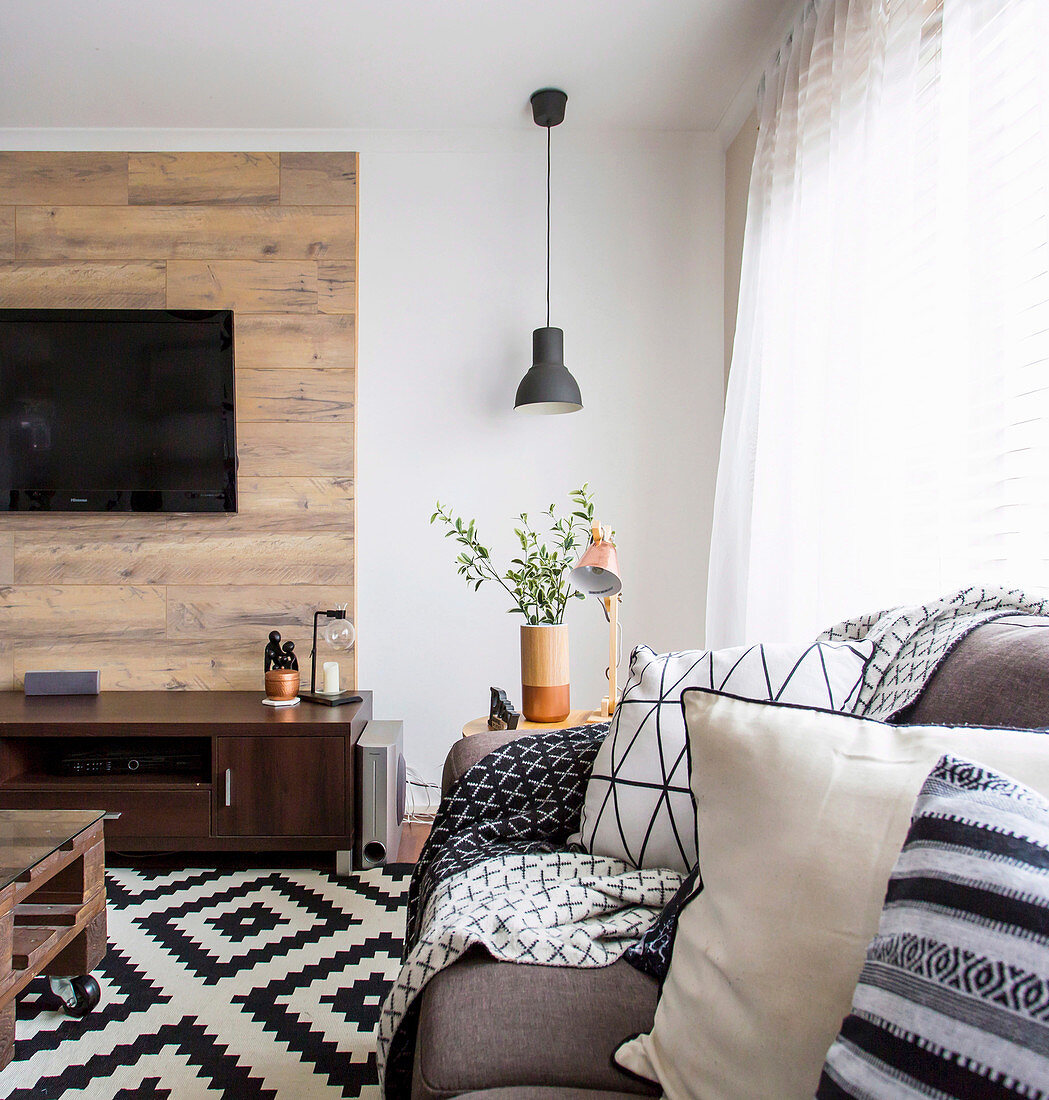 Sofa mit gemusterten Kissen und Holz verkleidete Wand