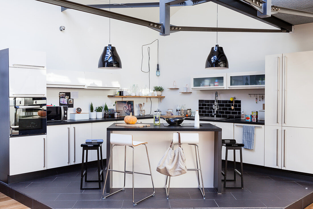 Offene Küche mit Kücheninsel auf Podest in offenem Wohnraum