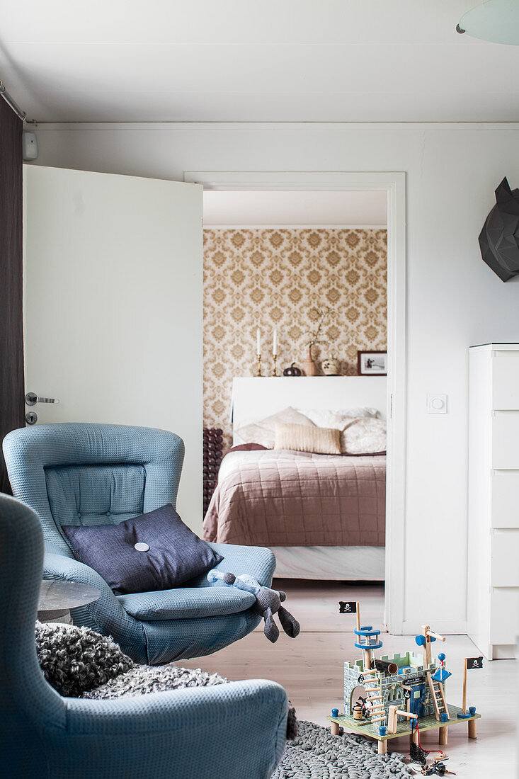 Two blue armchairs in front of open door leading into bedroom