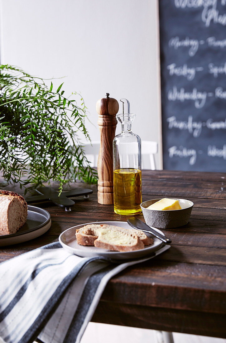 Olivenöl, Käse und Brot auf rustikalem Holztisch