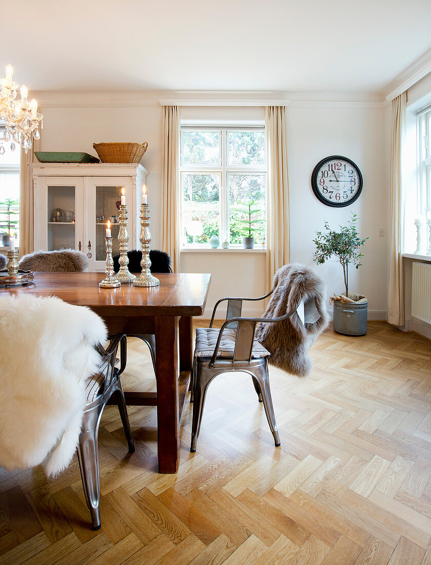 Sheepskins on metal chairs around wooden table in dining room
