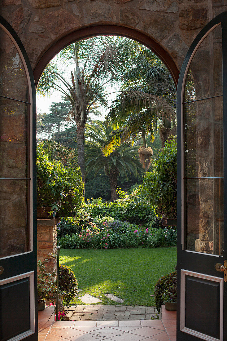 Blick durch eine Bogentür in den exotischen Palmengarten