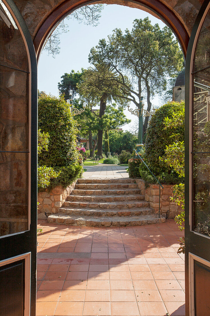 View through arched doorway across terrace and up steps into garden