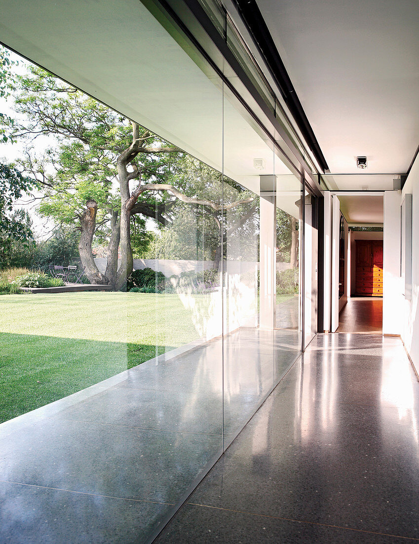 Corridor with glass wall overlooking garden with well-tended lawn