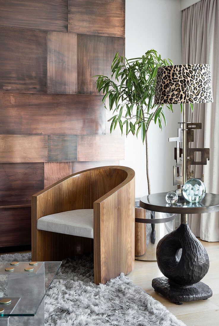Designerstuhl aus Holz, Beistelltisch und Zimmerbäumchen in Wohnzimmerecke