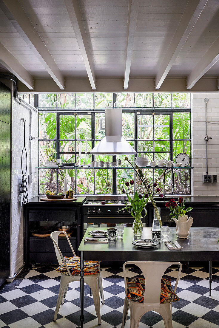 Gedeckter Tisch in schwarz-weißer Küche mit Fabrikfenster