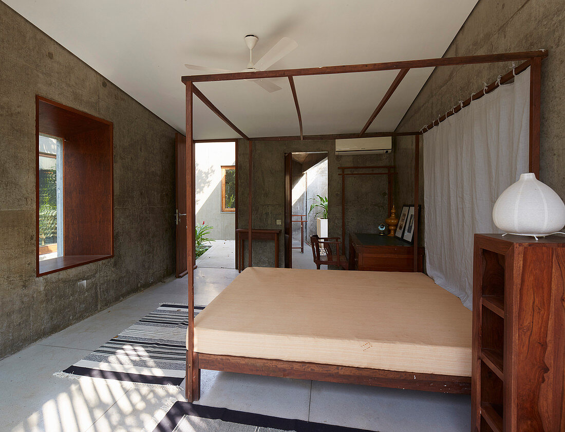 Four-poster bed and other wooden fittings in modern, concrete architect-designed house