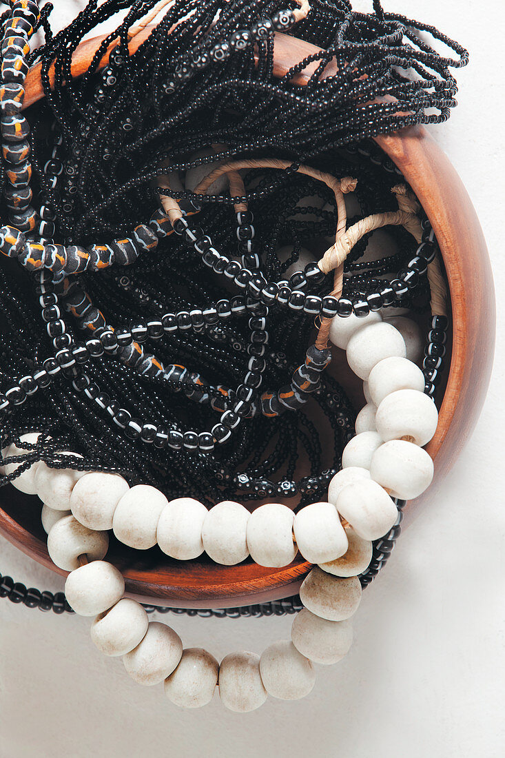 Various black and white necklaces in wooden bowl