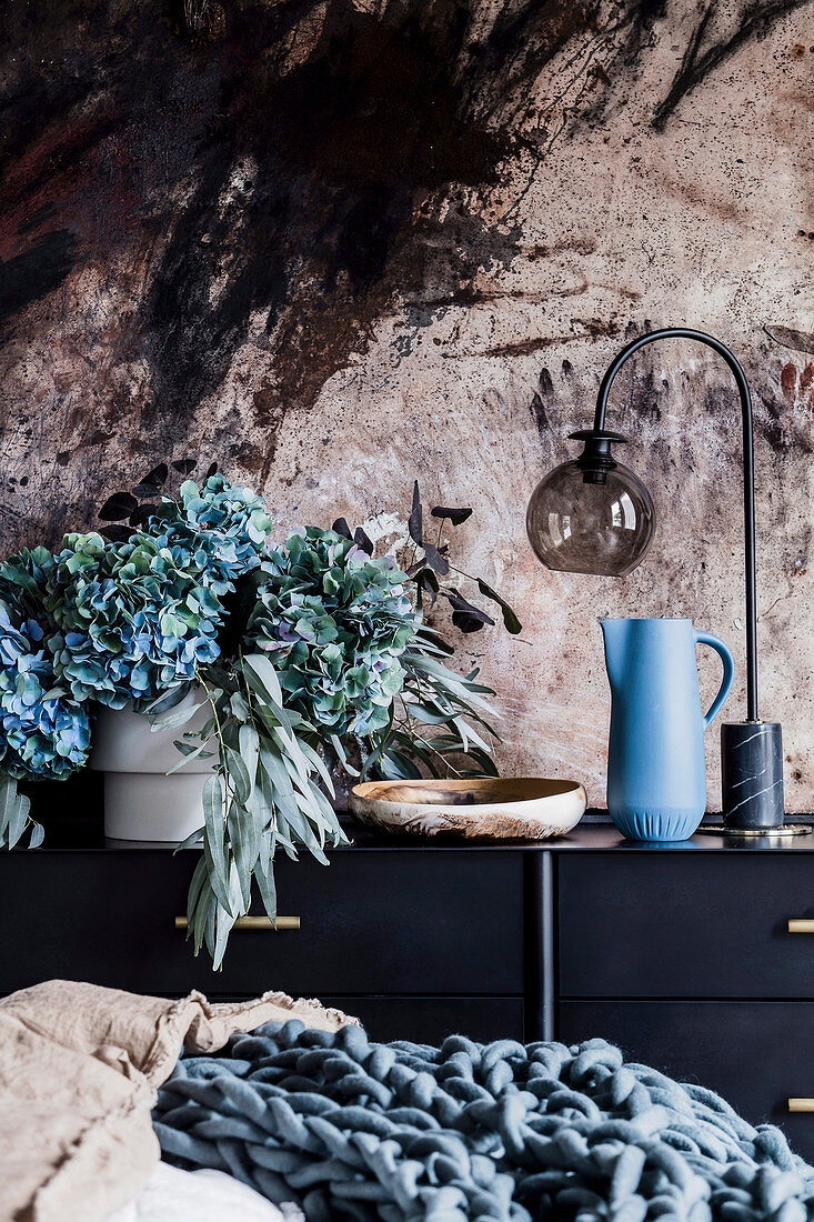 Vase mit Hortensien und Eucalyptuszweigen, Schale, Krug un Tischlampe auf Sideboard