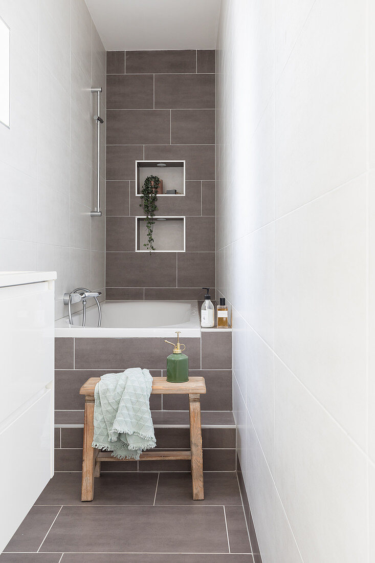 Badewanne in schmalem Badezimmer, teilweise mit hellgrauen Fliesen