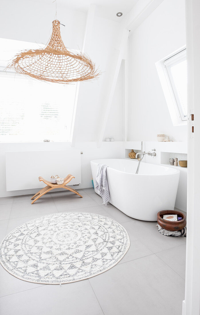 Free-standing bathtub and wicker lamp in bright bathroom
