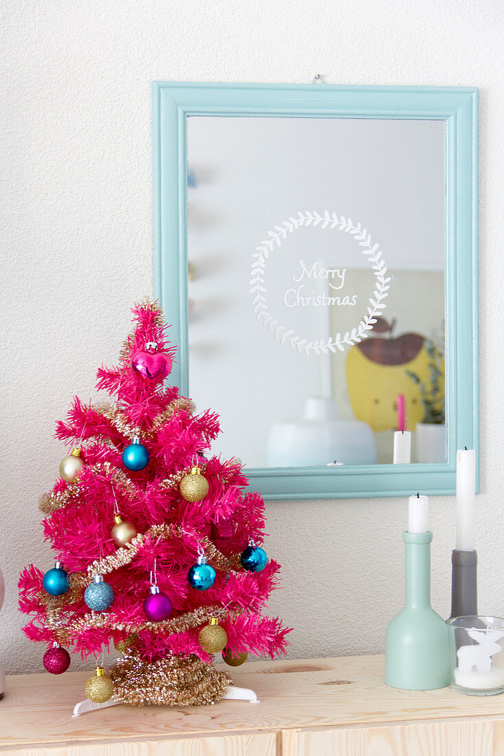 Pinker Weihnachtsbaum vor einem Spiegel mit Weihnachtsgruß