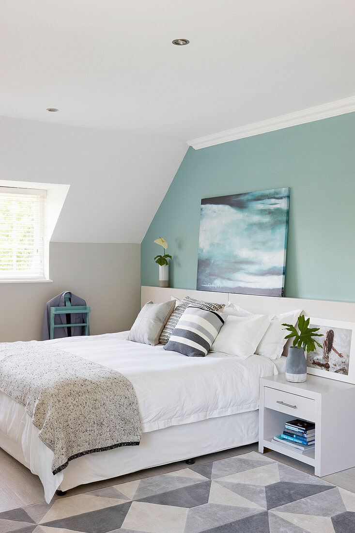 Schlafzimmer mit Doppelbett und hellgrüner Wand im Dachgeschoss