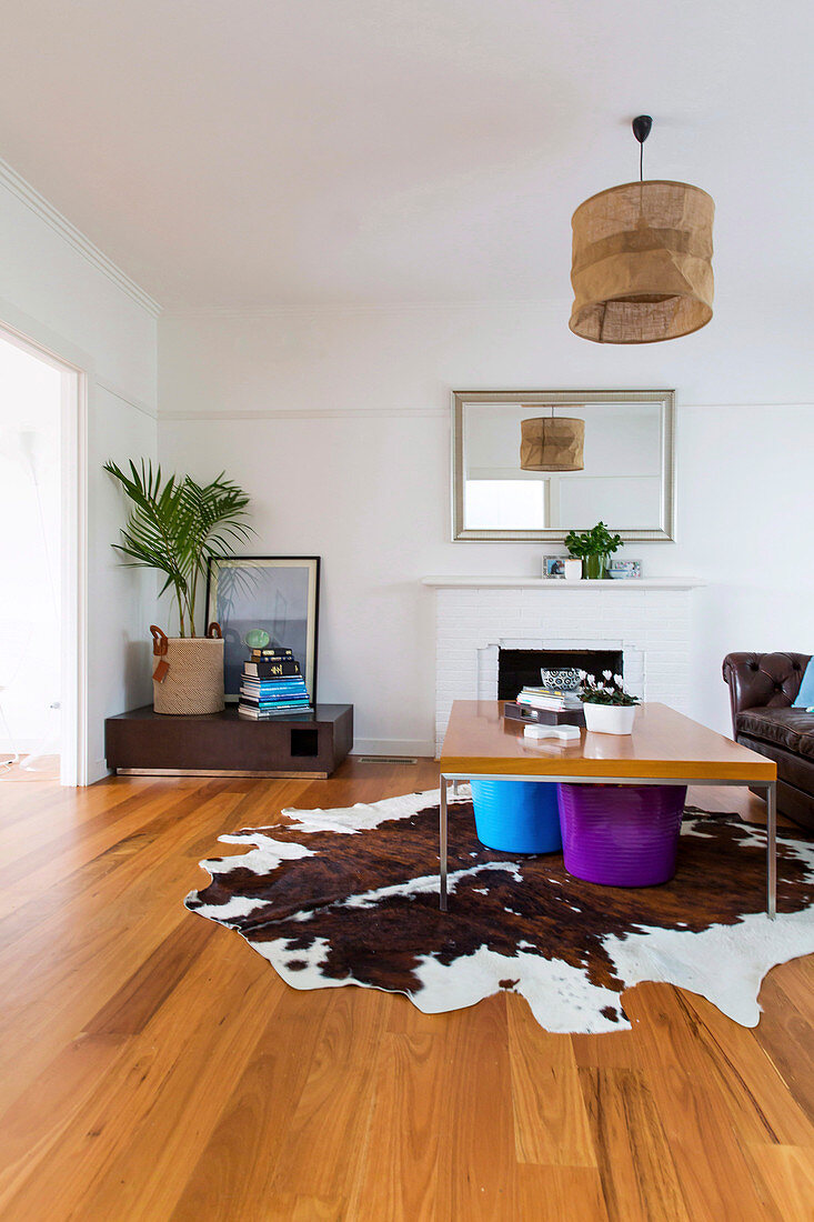 Colorful buckets under coffee table on animal fur rug in front of fireplace in living room