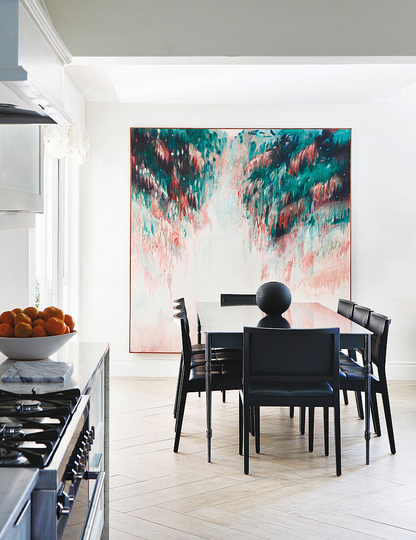 Black dining set in front of large artwork in open-plan kitchen