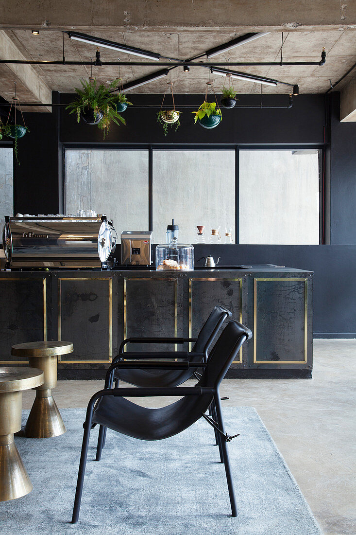 Vintage Bar mit schwarzen Stühlen und Tischchen in metallic Farben, vor schwarzer Theke