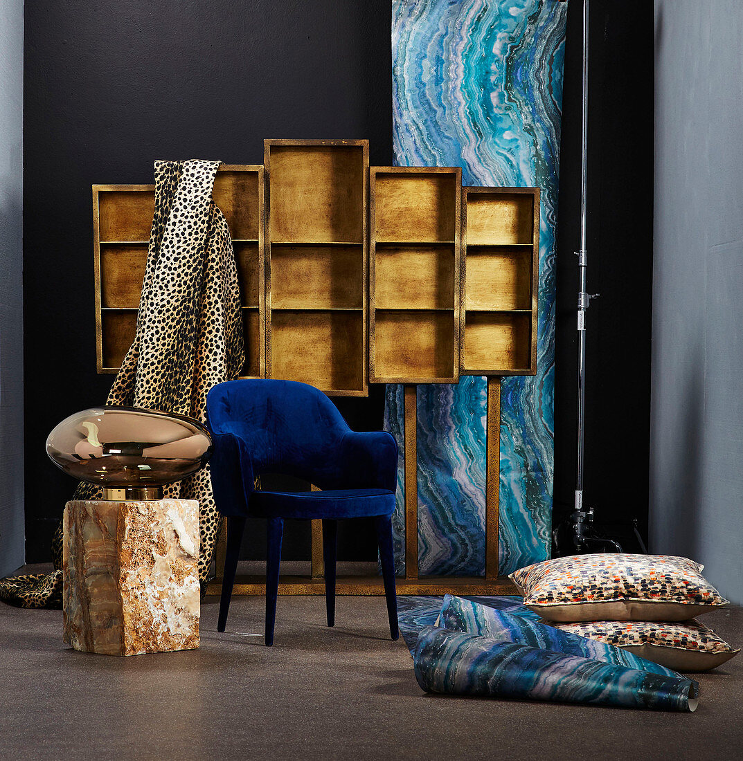 Luxuriöse Tapete und Stoffe, Bodenkisssen, blauer Stuhl und Leuchte in glänzender Metallausführung