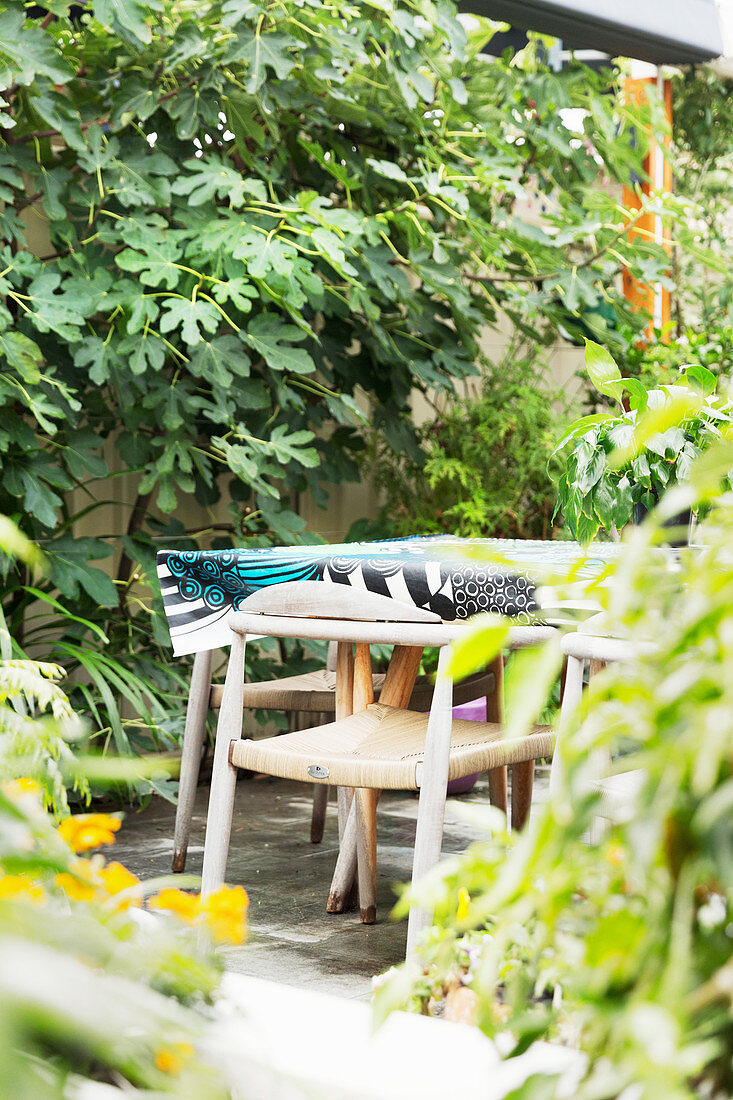 Holzstühle am Tisch mit Wachstuchtischdecke im Garten