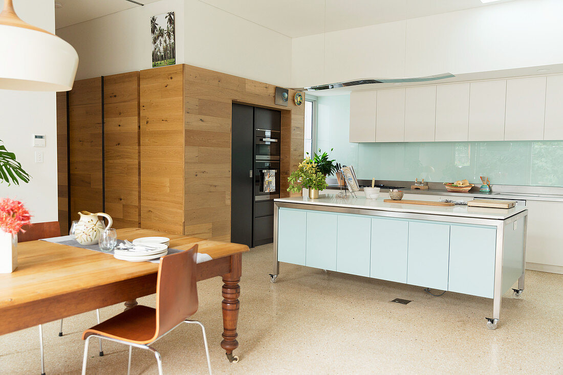 Holztisch vor moderner offener Küche und Wand mit Holzverkleidung