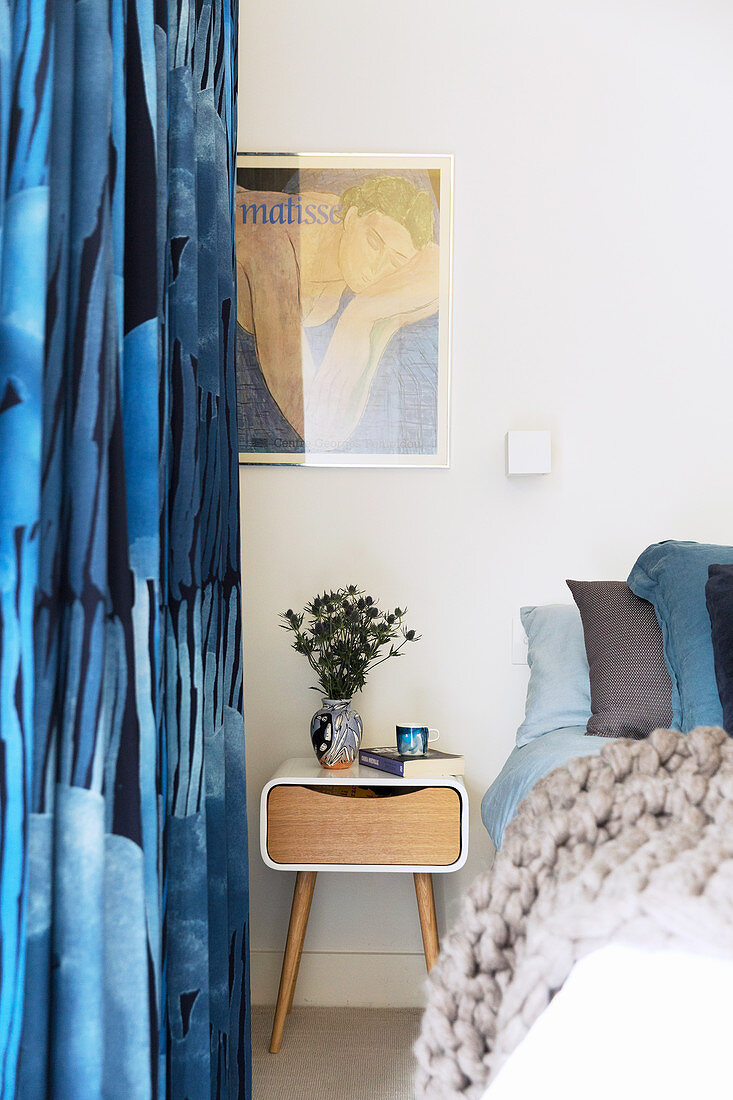 Blue patterned curtains next to the bed with a modern bedside table