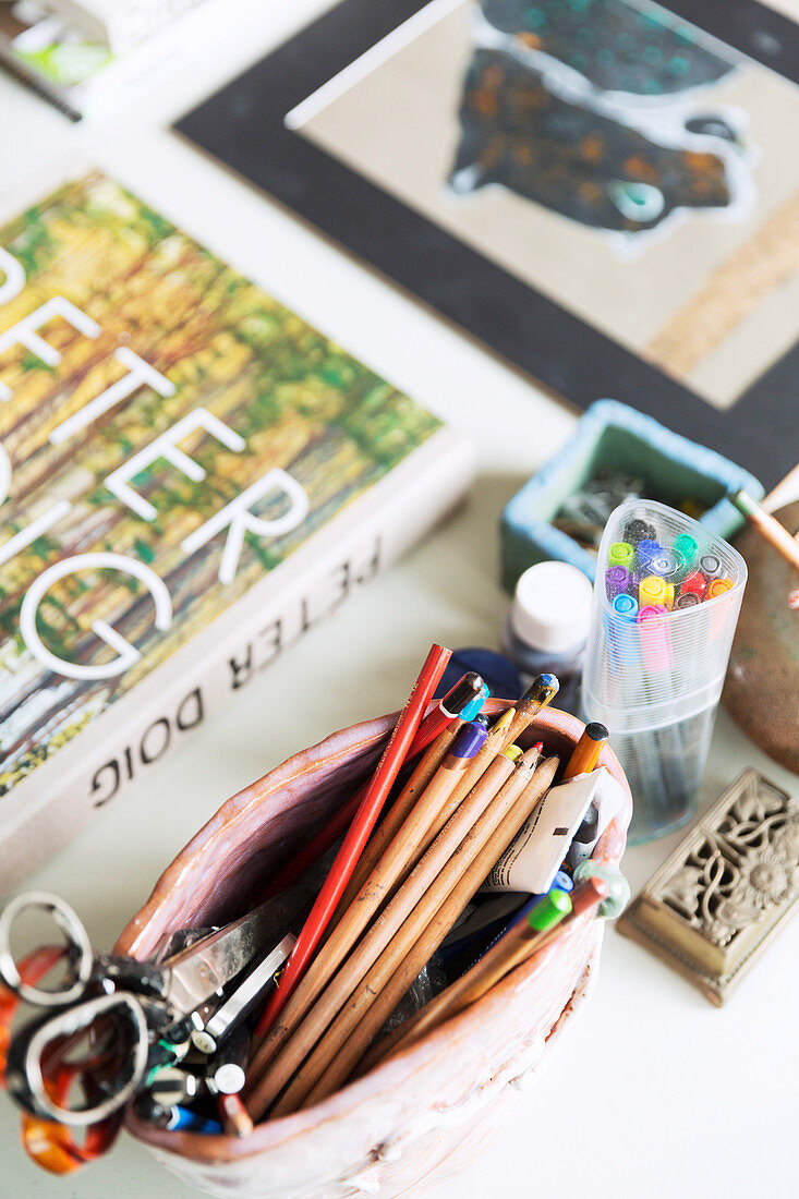 Pottery bowl with pens on the table with books