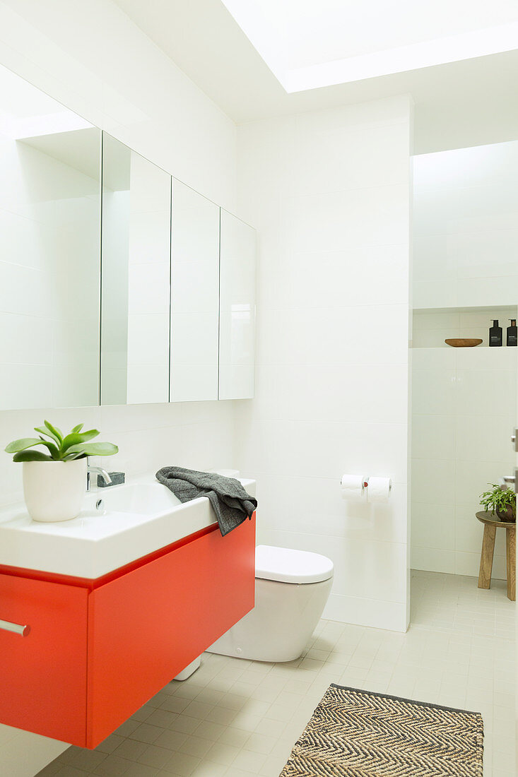 Roter Waschbeckenunterschrank als Farbakzent im modernen Bad