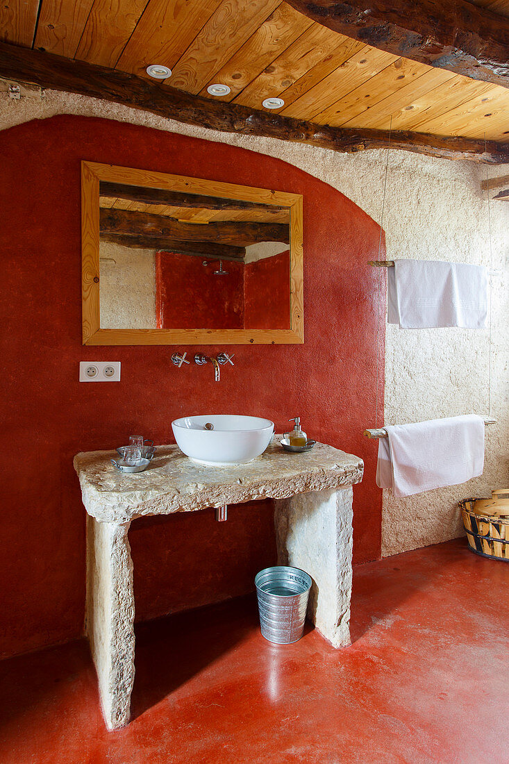 Concrete washstand with countertop sink in bathroom with red-painted floor and wall