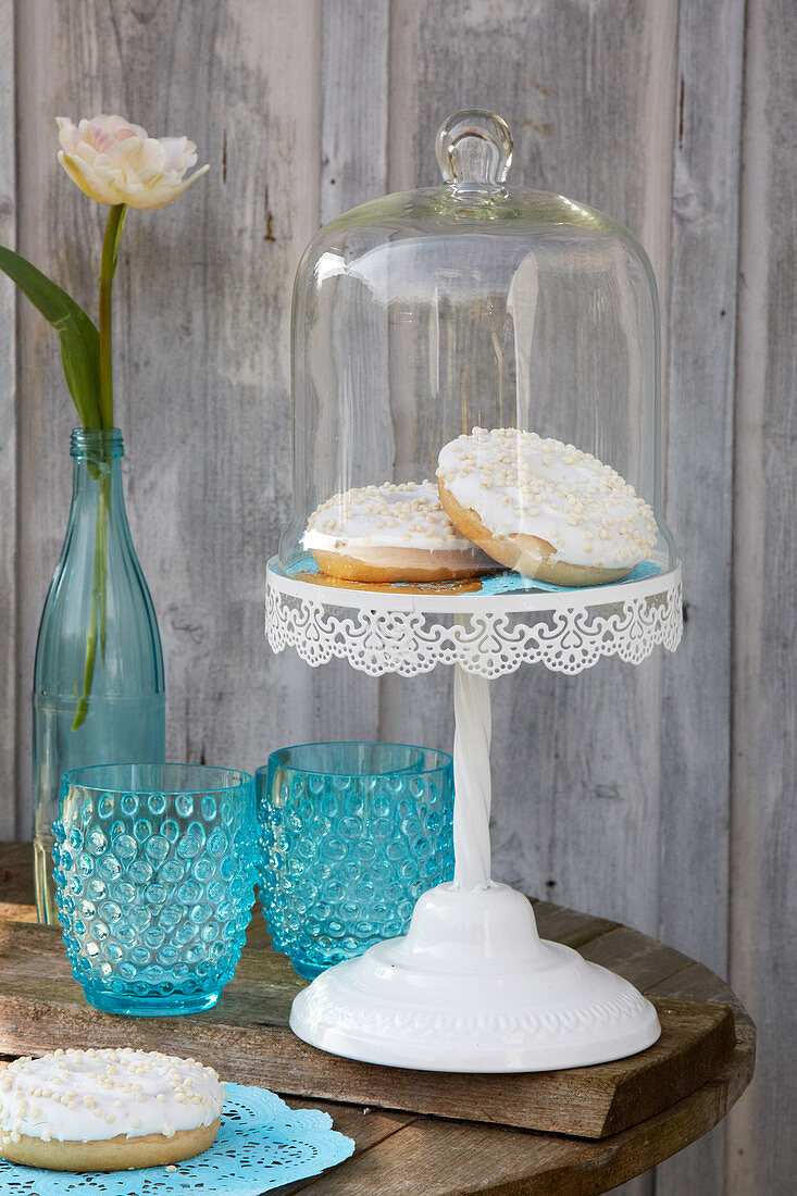 Donuts on blue doily under glass cover